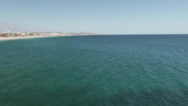 BUZZARDS EAST CAPE LOS CABOS BCS MEXICO-2022: Ocean Waves Approaching Sandy Beach with Coastal Buildings