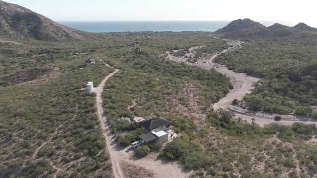 CABO PULMO BCS MEXICO-2022: Car Departing House on Arid Hillside Road