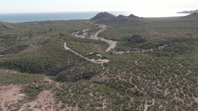 CABO PULMO BCS MEXICO-2022: Car Moving Along Winding Dirt Road in Hilly Landscape