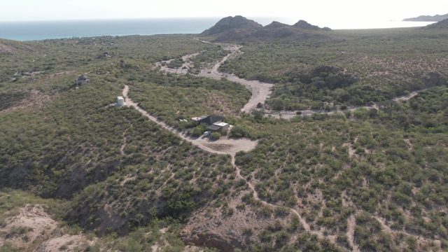 CABO PULMO BCS MEXICO-2022: Vehicle Moving Along Winding Dirt Road in Hilly Terrain