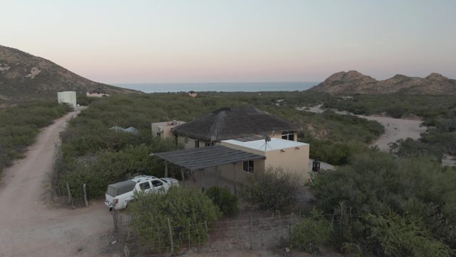 CABO PULMO BCS MEXICO-2022: White Pickup Truck Moving Along Coastal Dirt Road Past House