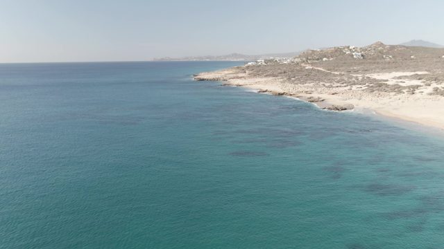 BUZZARDS EAST CAPE LOS CABOS BCS MEXICO-2022: Sandy Beach with Turquoise Waters and Hillside Buildings