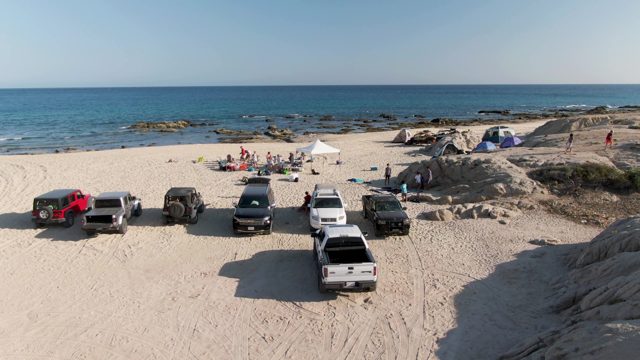 SHIPWRECKS BEACH EAST CAPE LOS CABOS BCS MEXICO-2022: People Moving Around Beach Campsite with Parked Vehicles