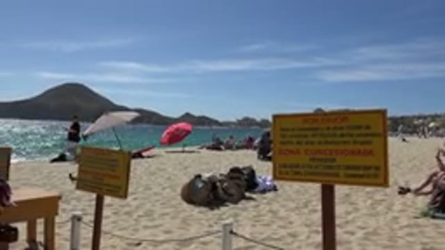 CABO SAN LUCAS MEXICO-2017: Man Walking Near Sign And Umbrellas On Scenic Beach