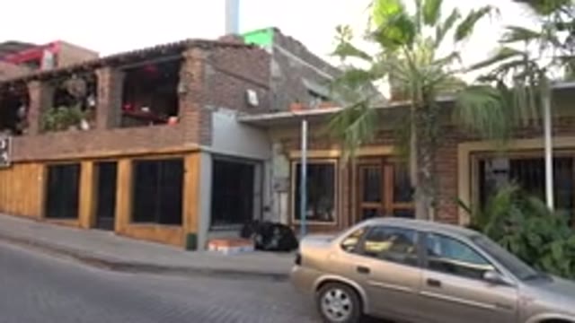 LOS CABOS MEXICO-2017: A View Of A Brown Building From The Road With A Car Parked