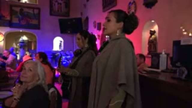 LOS CABOS MEXICO-2017: Woman Singing In Crowded Room With Guitar Accompanying
