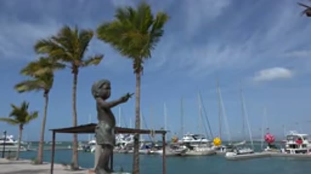 LOS CABOS MEXICO-2017: Statue Of A Young Boy On A Boat Dock With Palm Trees