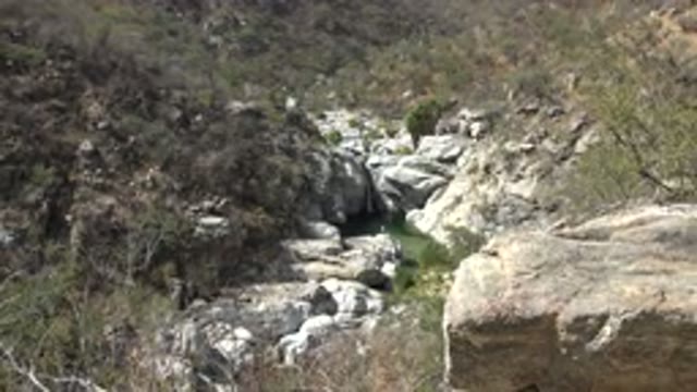 LOS CABOS MEXICO-2017: Rocky Cave on a Mountain Slopeside Among Dry Shrubs