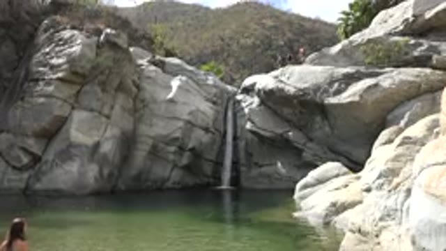 LOS CABOS MEXICO-2017: Waterfall Tumbling Down Rocks Into Pool Of Green Water