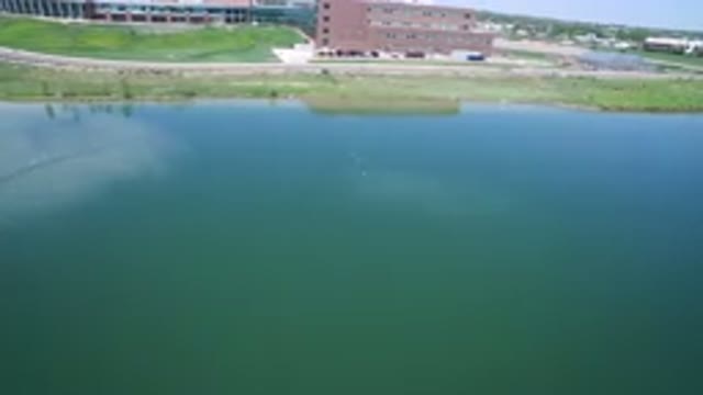 WESTMINSTER COLORADO-2017: Road With Cars Alongside Large Clean Lake And Brick Buildings