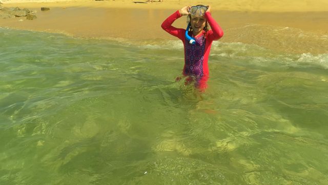 SAN JOSE DEL CABO BCS MEXICO-2023: Child Adjusting Snorkel Mask in Shallow Beach Water