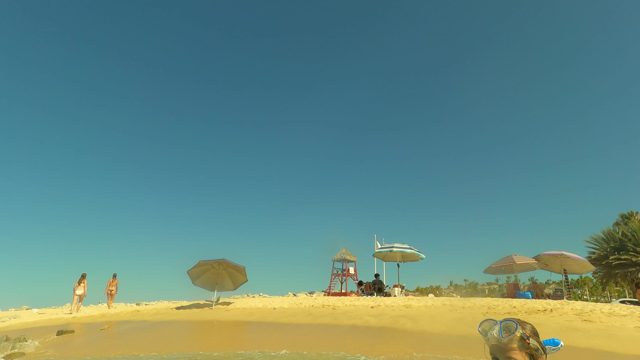 SAN JOSE DEL CABO BCS MEXICO-2023: People Walking Along Beach with Umbrellas and Lifeguard Tower