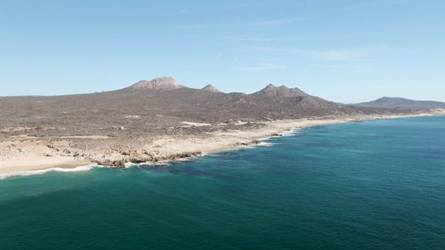 BUZZARDS BEACH EAST CAPE BCS-2023: Waves Lapping a Sandy Beach with Mountain Backdrop