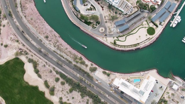 LA PAZ BCS-2023: Small Boat Navigating Curved Canal Beside Road and Marina