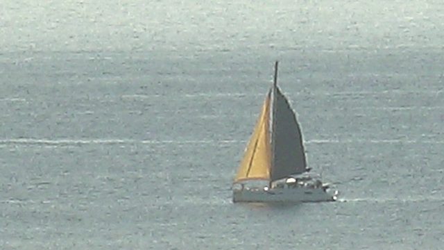Sailboat with Yellow and Dark Sails Moving on Calm Water