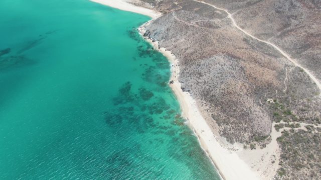 Sandy Beach and Turquoise Ocean Along Rocky Coastline