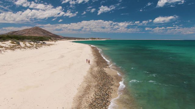 Two People Walking on a White Sand Beach