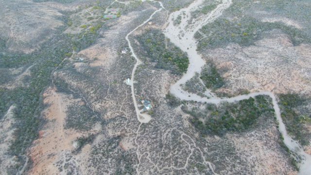 Vehicle Traveling on Winding Dirt Road Through Dry Terrain