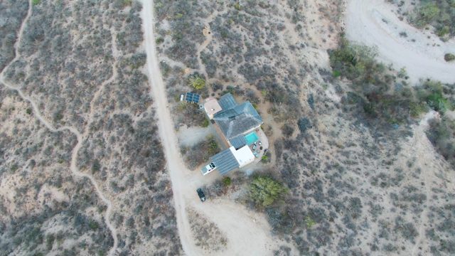 Desert House with Vehicle Driving on Dirt Road