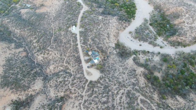 Vehicle Traveling on Arid Hillside Dirt Road