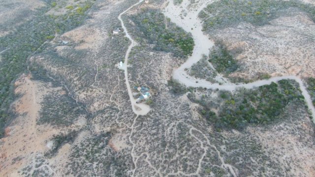Vehicle Traveling on Winding Dirt Road Through Dry Hills
