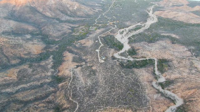 Arid Hills and Winding River with Vehicle Movement