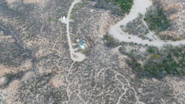 Arid Landscape with Small Structures and Winding Dirt Road