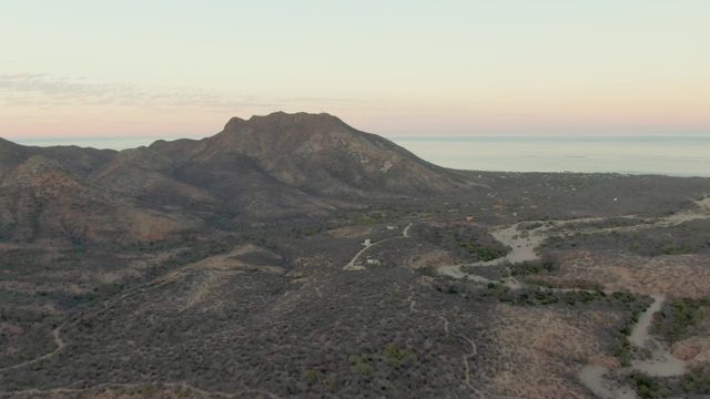 Arid Mountain Range with Winding Roads and Distant Ocean