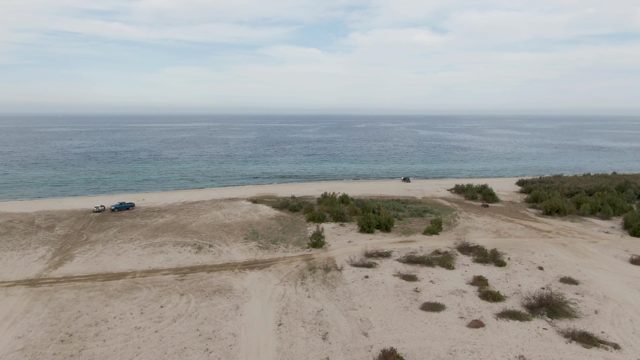 Vehicles Driving on Sandy Beach by Ocean