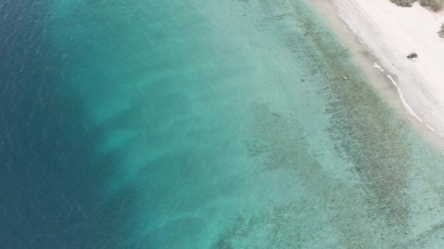 Small Boat Departing Sandy Shore Into Clear Ocean