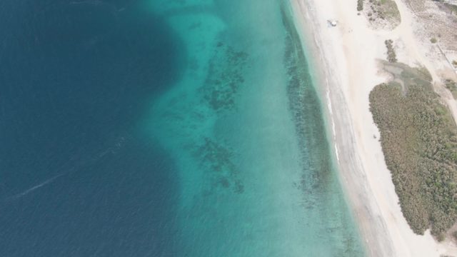 Vehicle Traveling on Beach Road Beside Clear Ocean Waters