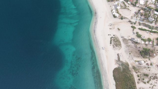 Sandy Shoreline with Clear Blue Ocean and Coastal Development