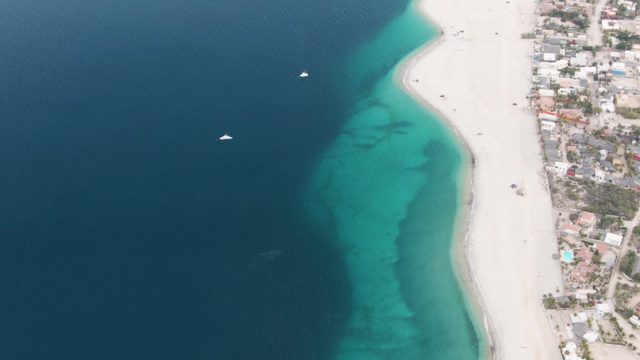 Coastal Beach with Boats Moving in Clear Water