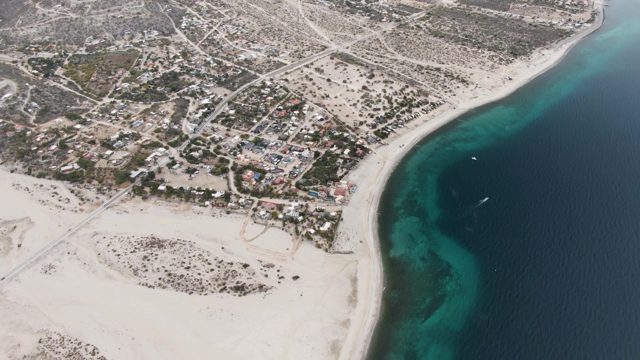 Coastal Settlement with Boat Moving Along Shore