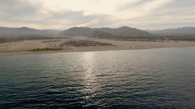 Sandy Beach and Calm Ocean with Distant Mountains