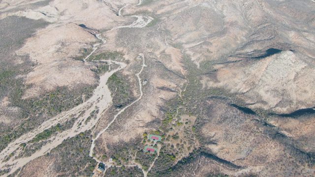 Vehicle Traveling on Winding Dirt Road in Arid Hills