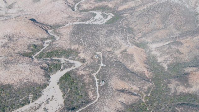 Car Driving on Winding Road Through Arid Hills