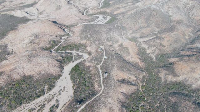 Vehicle Moving Along Winding Dirt Road in Arid Hills