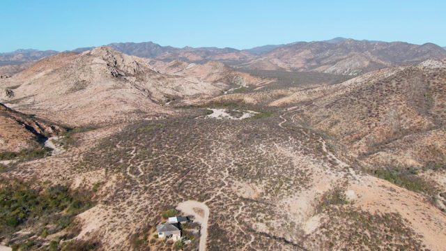 Desert Valley with Isolated House and Distant Mountains