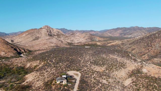A House in a Desert Valley As a Vehicle Departs