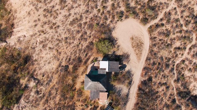 House in Arid Desert with Winding Dirt Roads