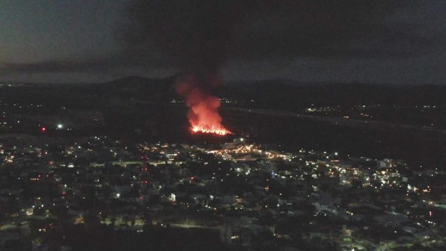 Nighttime Fire Near Urban Area with Rising Smoke