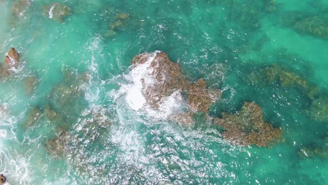 Waves Crashing Against Rocky Seabed in Turquoise Water