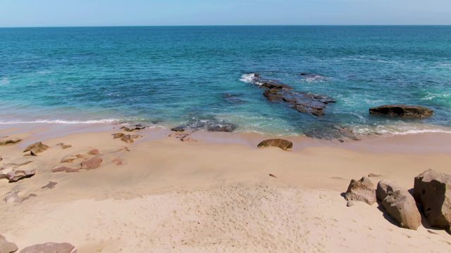 Sandy Beach with Turquoise Ocean and Rocky Outcrops