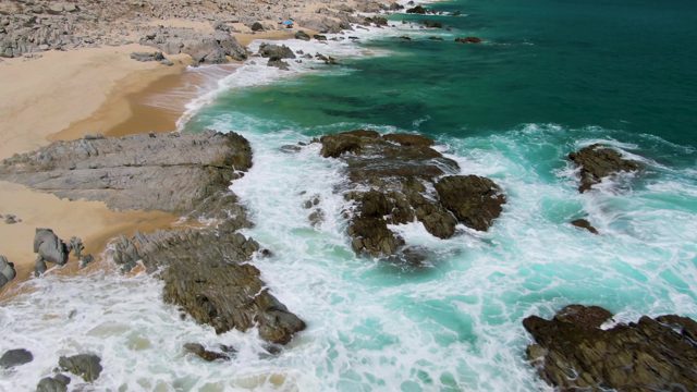 Waves Crashing on Rocky Shoreline with Sandy Beach