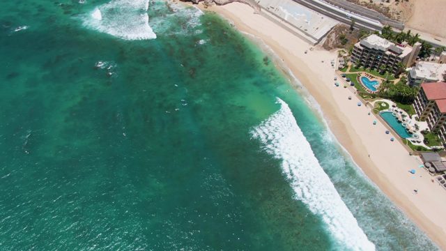 Waves Rolling Onto Sandy Beach with Coastal Buildings