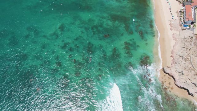 Waves Crashing on Sandy Shore From Above