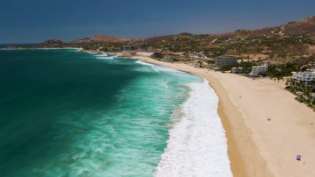 Waves Rolling Onto Sandy Beach with Coastal Buildings