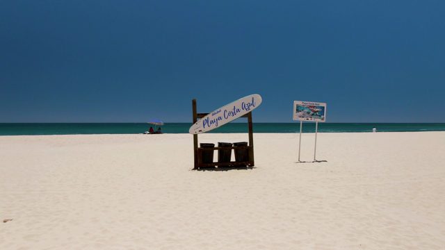 Sandy Beach with Sign and Calm Ocean View