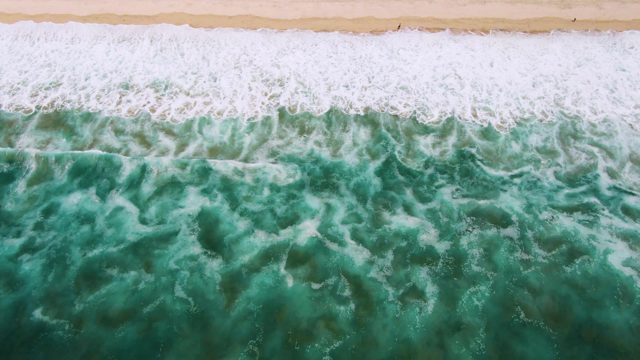 Waves Rolling Onto Sandy Shore From Above